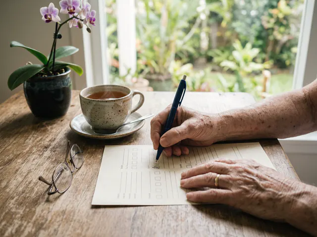 Hands filling in a paper form with a pen